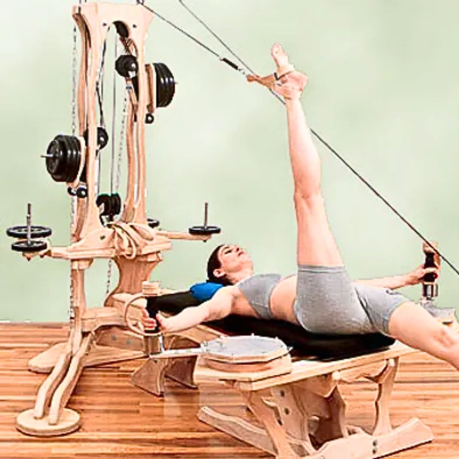 Esercizio disteso sulla Pulley Tower, le gambe sollevate e le cinghie alle caviglie