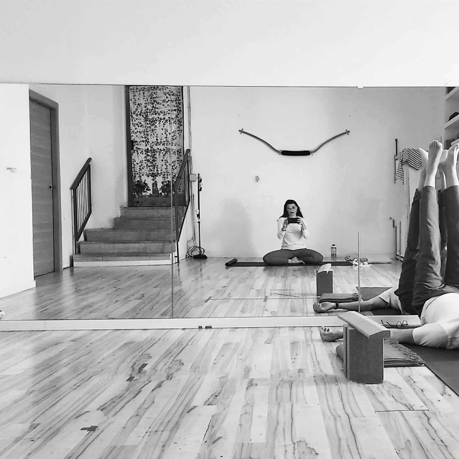 La sala dello studio in bianco e nero: pavimento in legno, specchio a parete e la scala d'ingresso
