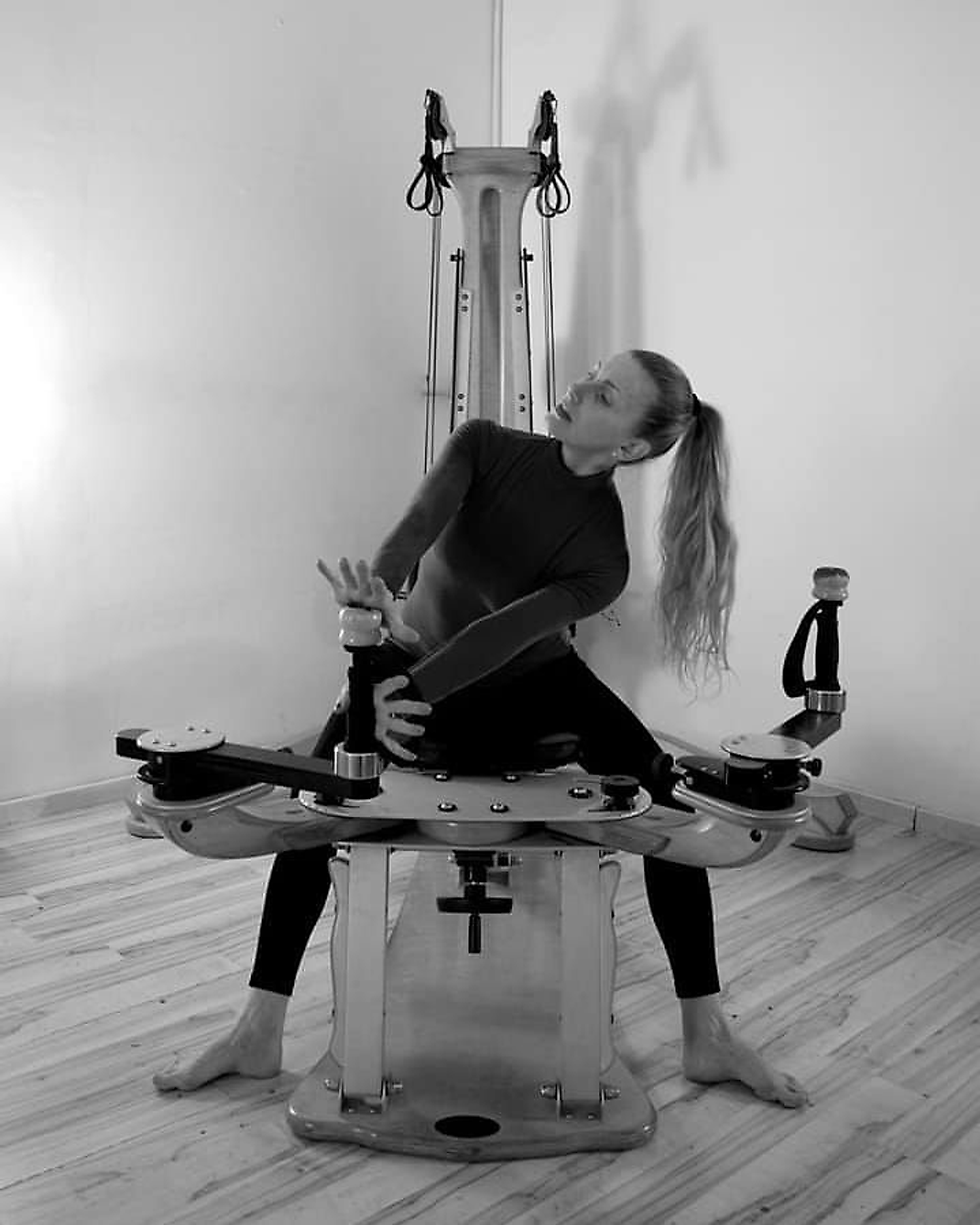 Una donna lavora sulla Pulley Tower dello studio, il busto in torsione e le braccia alle cinghie